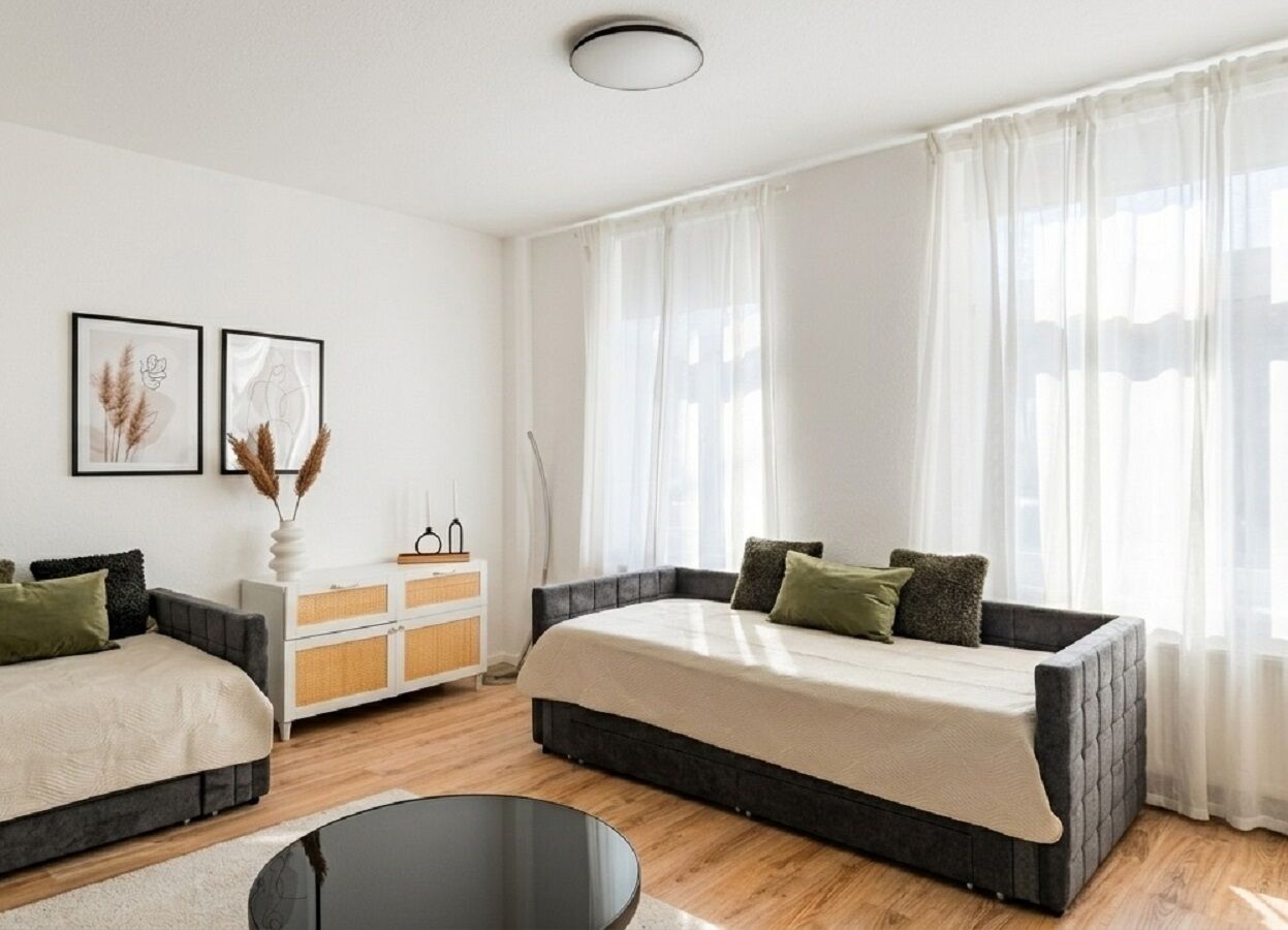 A modern bedroom with a large bed, a sofa, a small table, and a cabinet.