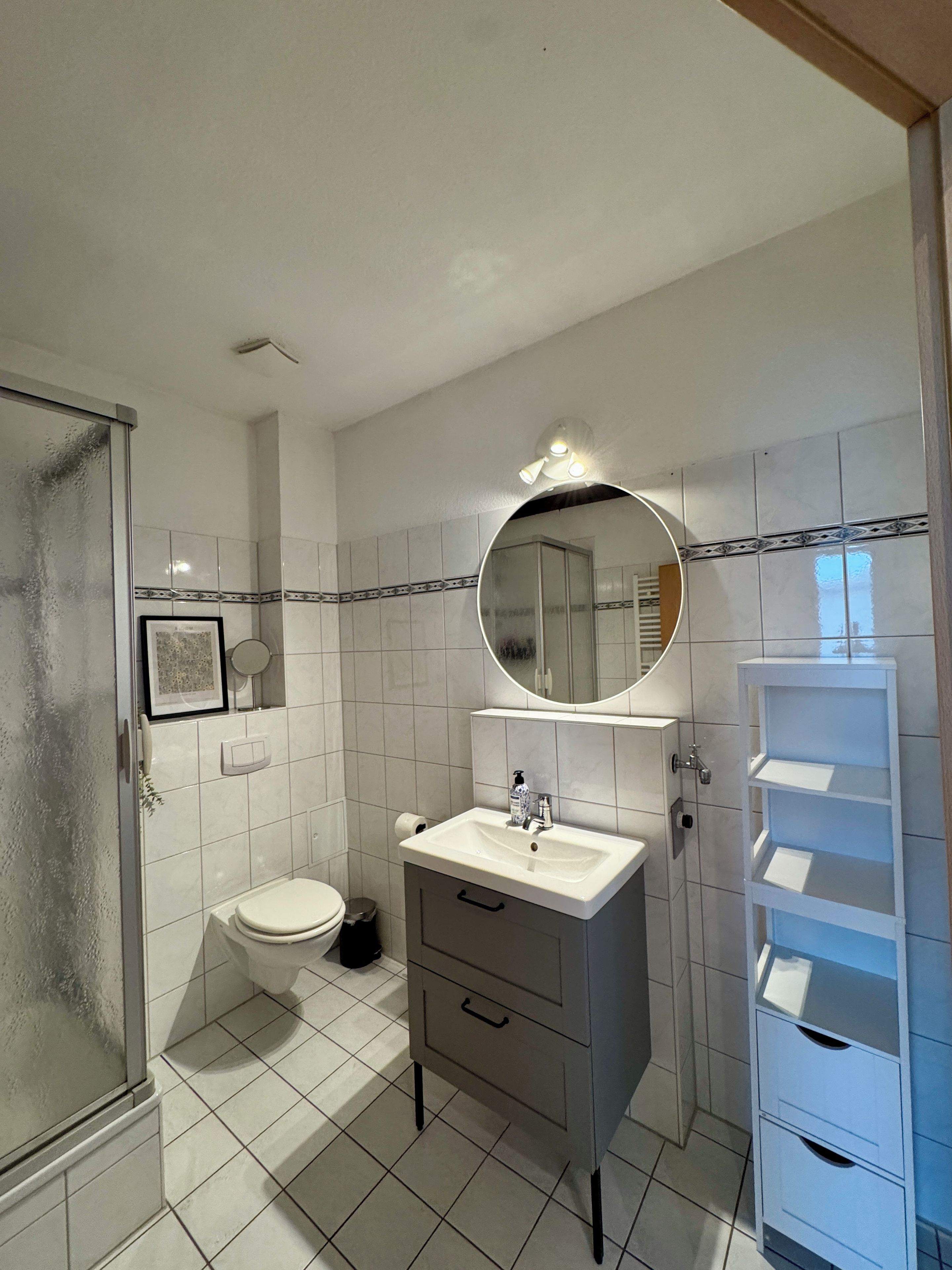 A bathroom with a toilet, sink, mirror, and a shower area.