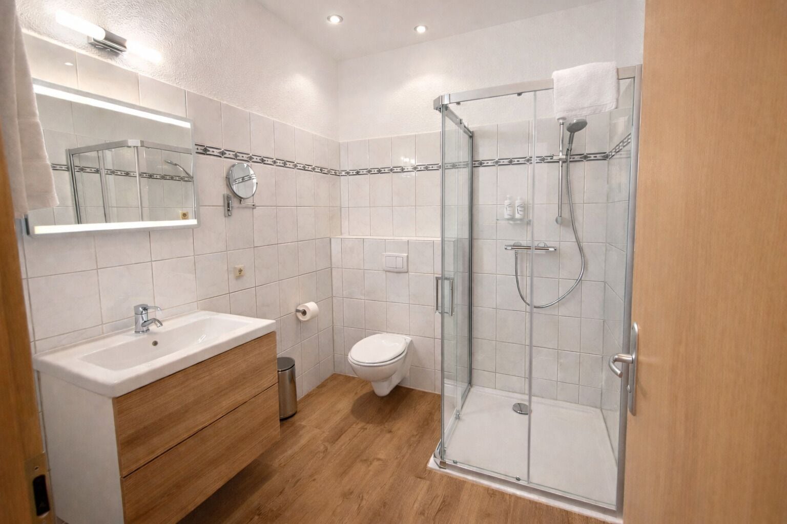 A modern bathroom with a glass shower enclosure, a sink with a mirror, and a toilet.