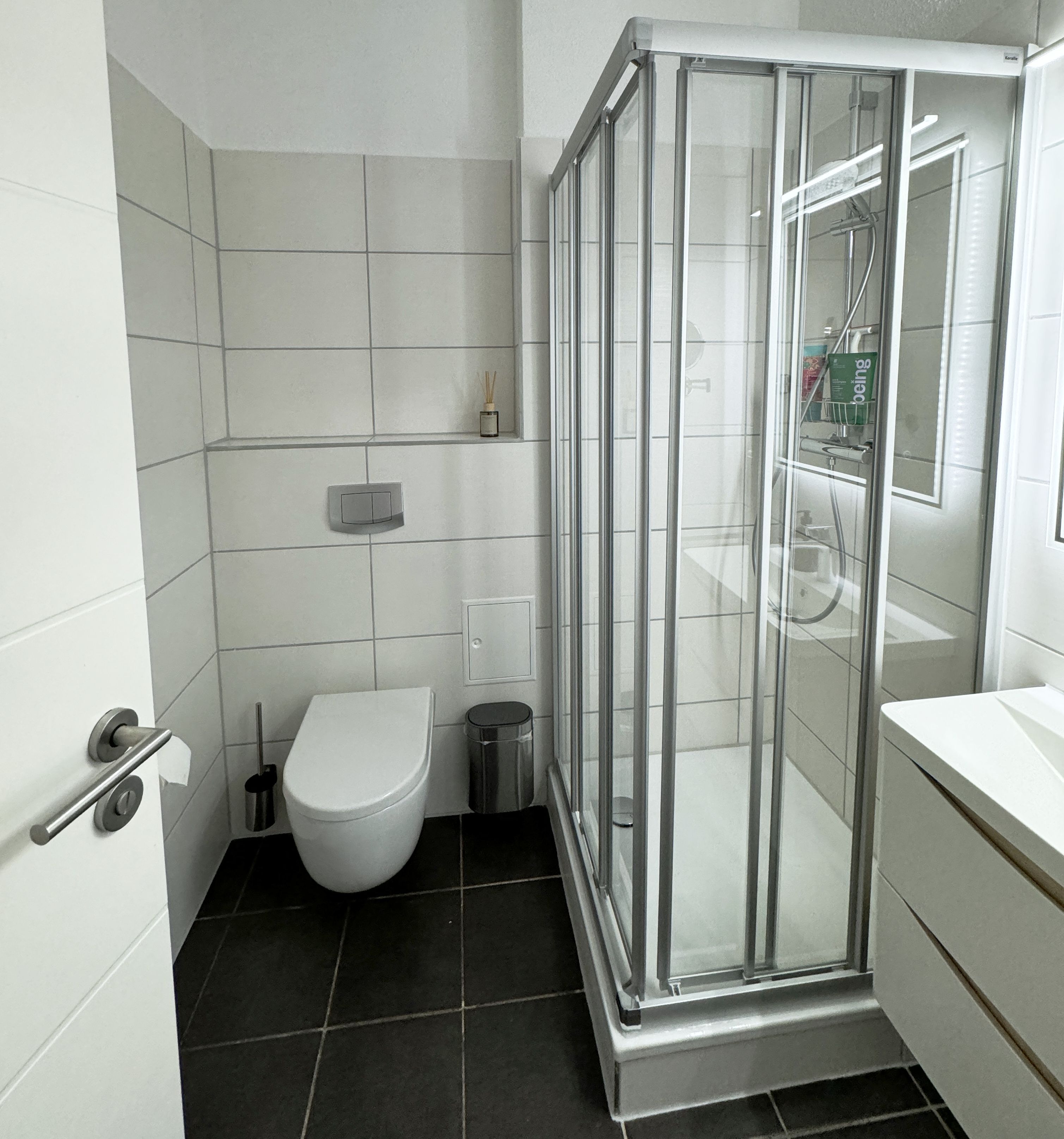 Un baño moderno con ducha de vidrio, inodoro y lavamanos.