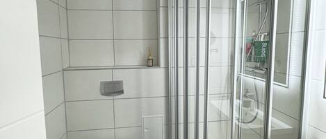 Un baño moderno con ducha de vidrio, inodoro y lavamanos.