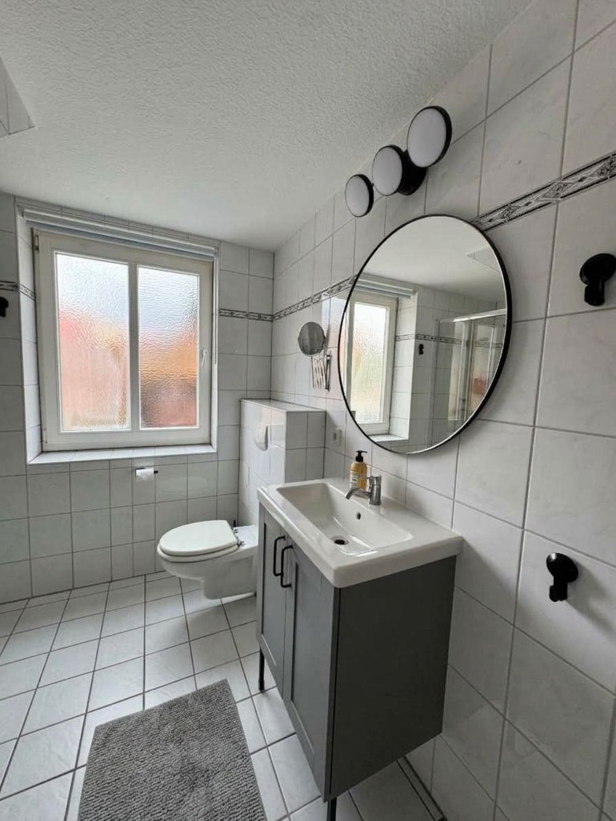 A bathroom with a toilet, sink, and mirror.