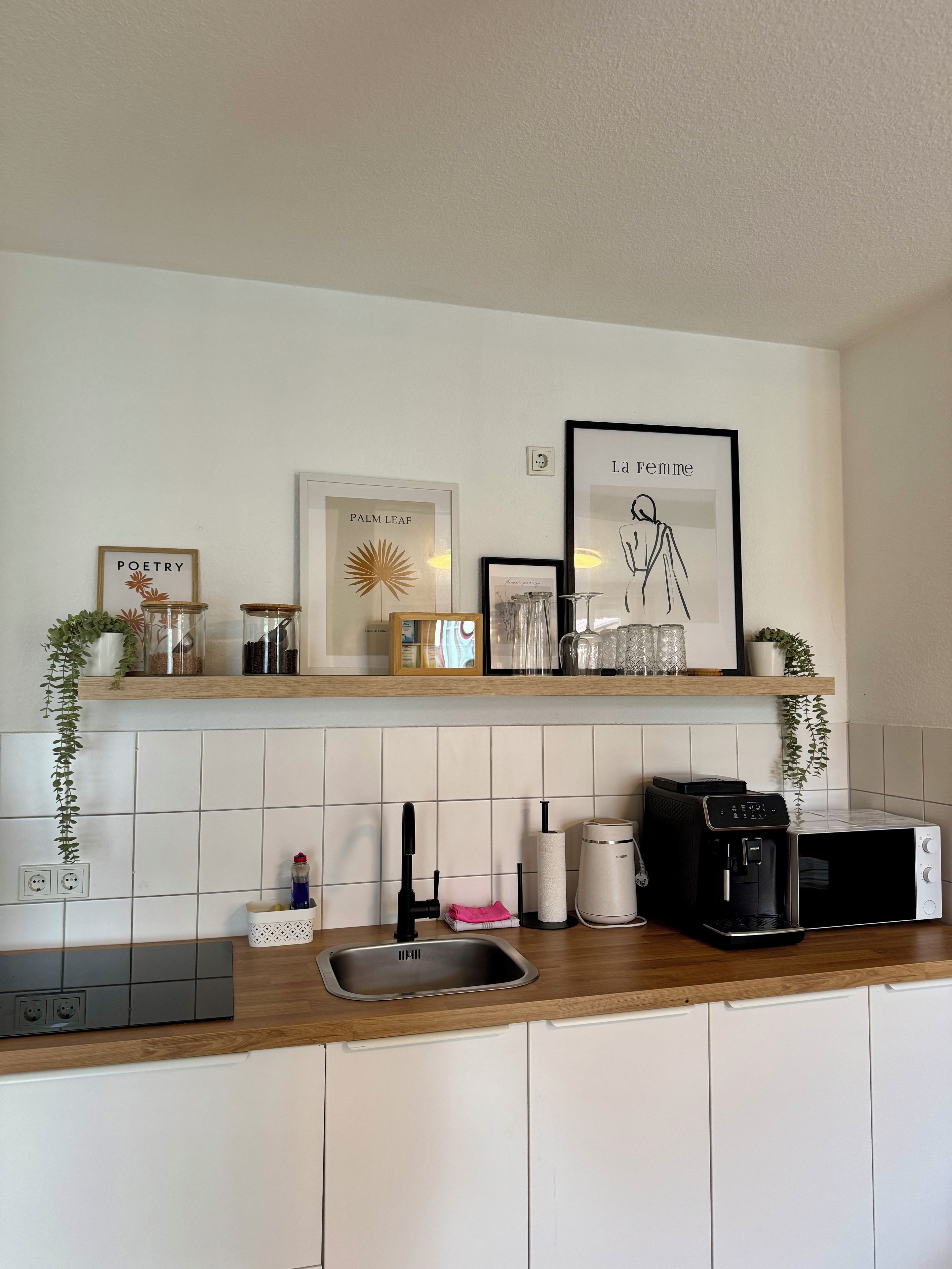Eine Küche mit Holzausziehtisch, Spüle aus Edelstahl, Kaffeemaschine und Mikrowelle.