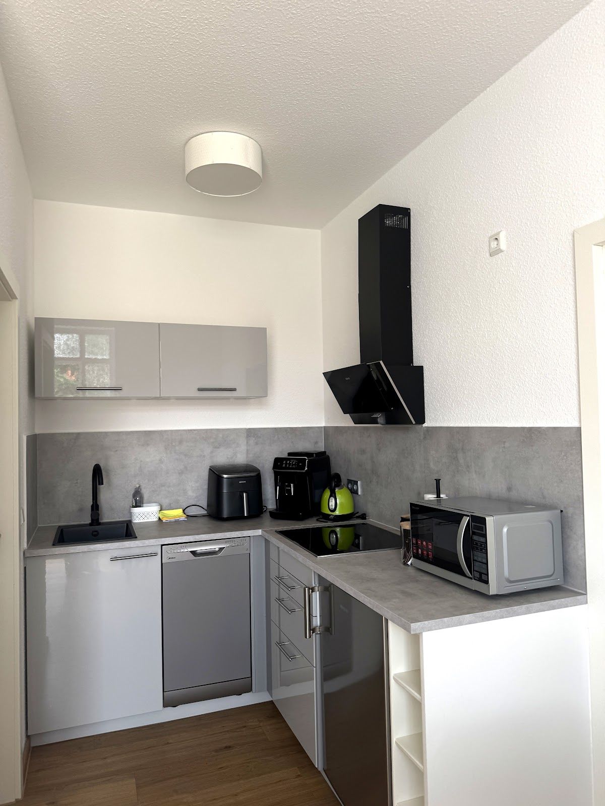 Cozinha compacta equipada com lava-louças, cafeteira, chaleira e micro-ondas.