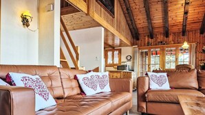 A cozy living room with leather sofas, a wooden table, and a rustic ceiling.