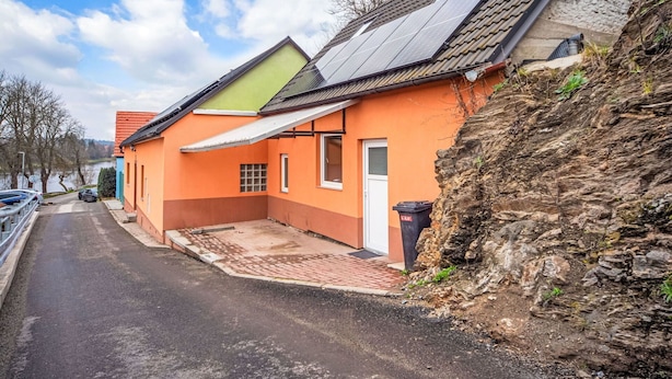 Un immeuble résidentiel doté d’un toit en pente, de panneaux solaires et d’une allée pavée.