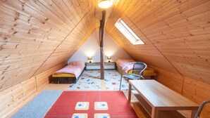 Une chambre confortable située dans les combles, avec des murs en bois, deux lits, un bureau et une fenêtre.