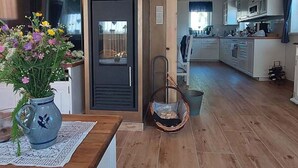 A modern kitchen with white cabinets, a wooden floor, and a view into the dining area.