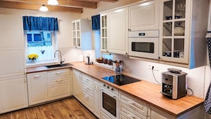 A kitchen with wooden cabinets, a built-in oven, a microwave, and a coffee machine.