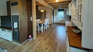 A spacious kitchen with wooden flooring, white cabinets, and a dining area with a wooden table and chairs.
