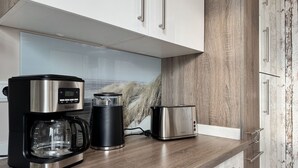 A modern kitchen with a coffee maker, a toaster, and a kettle on a wooden countertop. - Nice apartment for 2 people with WIFI, hot tub, TV, patio and pets allowed (Steinheim)