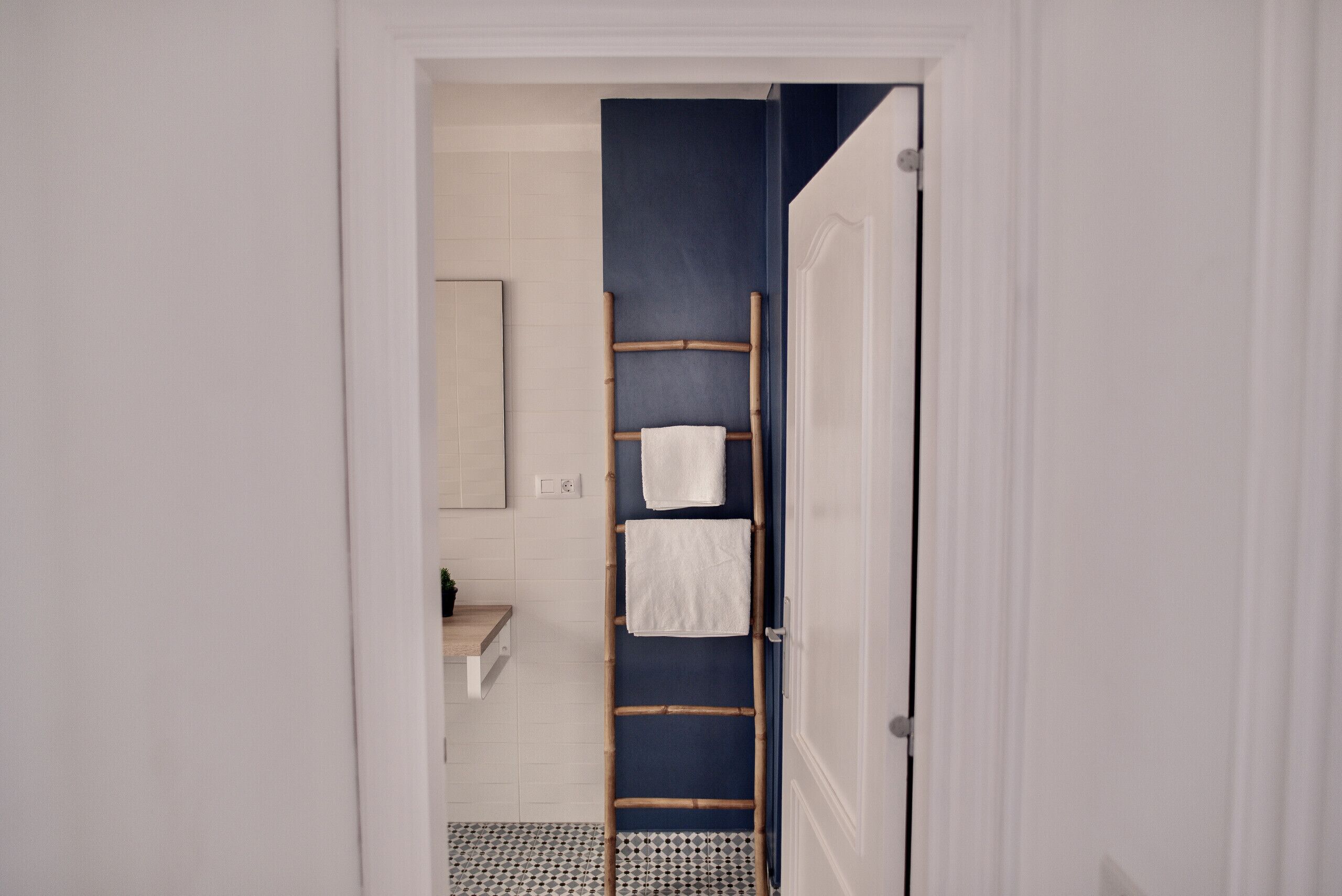 A bathroom with a white sink, a mirror, and a towel rack with two towels.