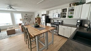 Una cocina moderna con armarios blancos, electrodomésticos de acero inoxidable y una mesa de comedor de madera.