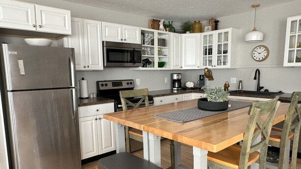 Una cocina moderna con armarios blancos, electrodomésticos de acero inoxidable y una mesa de comedor de madera con sillas.