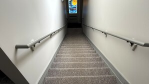A carpeted stairway with handrails and a door at the top.