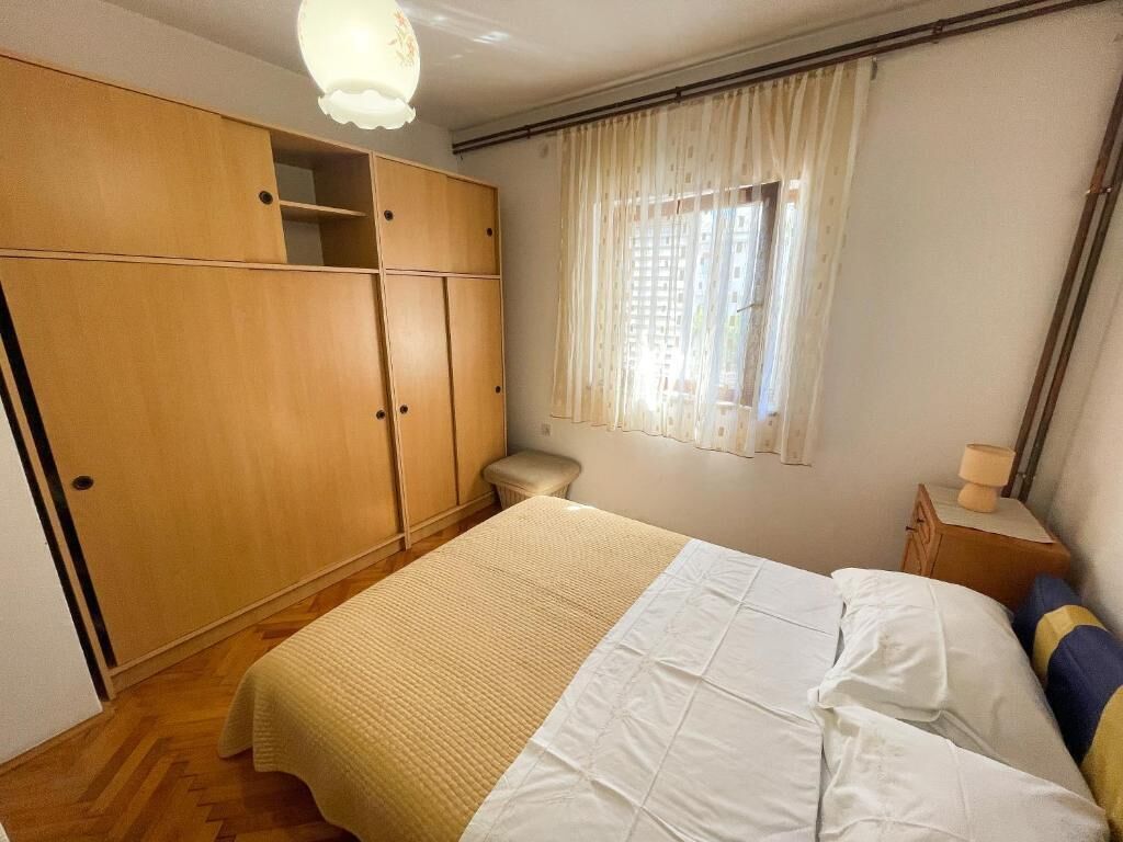 A bedroom with a bed, wooden wardrobe, and a window with curtains.