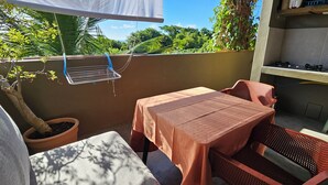 Un pequeño espacio al aire libre con mesa y sillas, una planta en maceta y un tendedero.