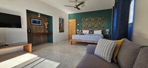 A modern bedroom with a bed, a sofa, a TV, and artwork on the walls.