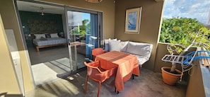 Ein Balkon mit Tisch, Stühlen, einer Couch und einem Blumentopf.