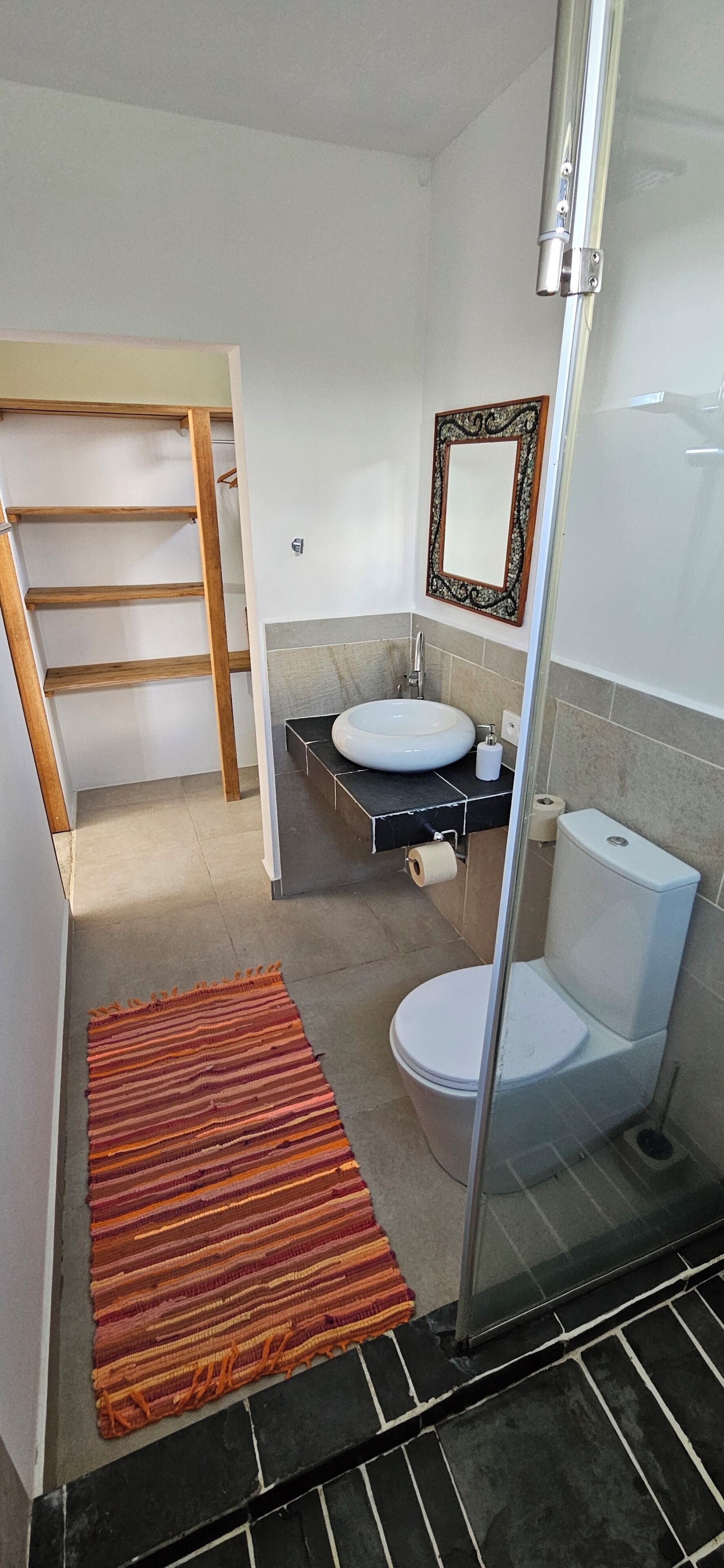 A compact bathroom with a toilet, sink, and a mirror.