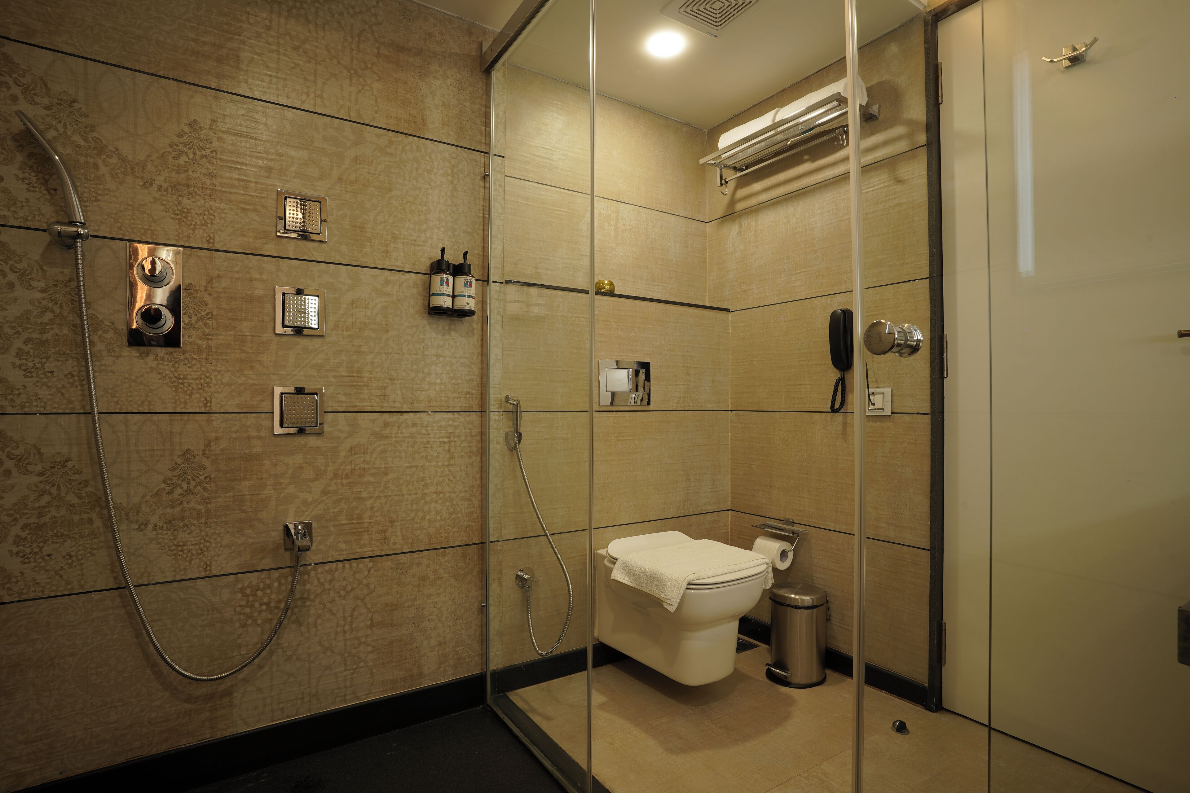 A modern bathroom with a glass-enclosed shower, a toilet, and a trash can.