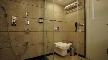 A modern bathroom with a glass-enclosed shower, a toilet, and a trash can.