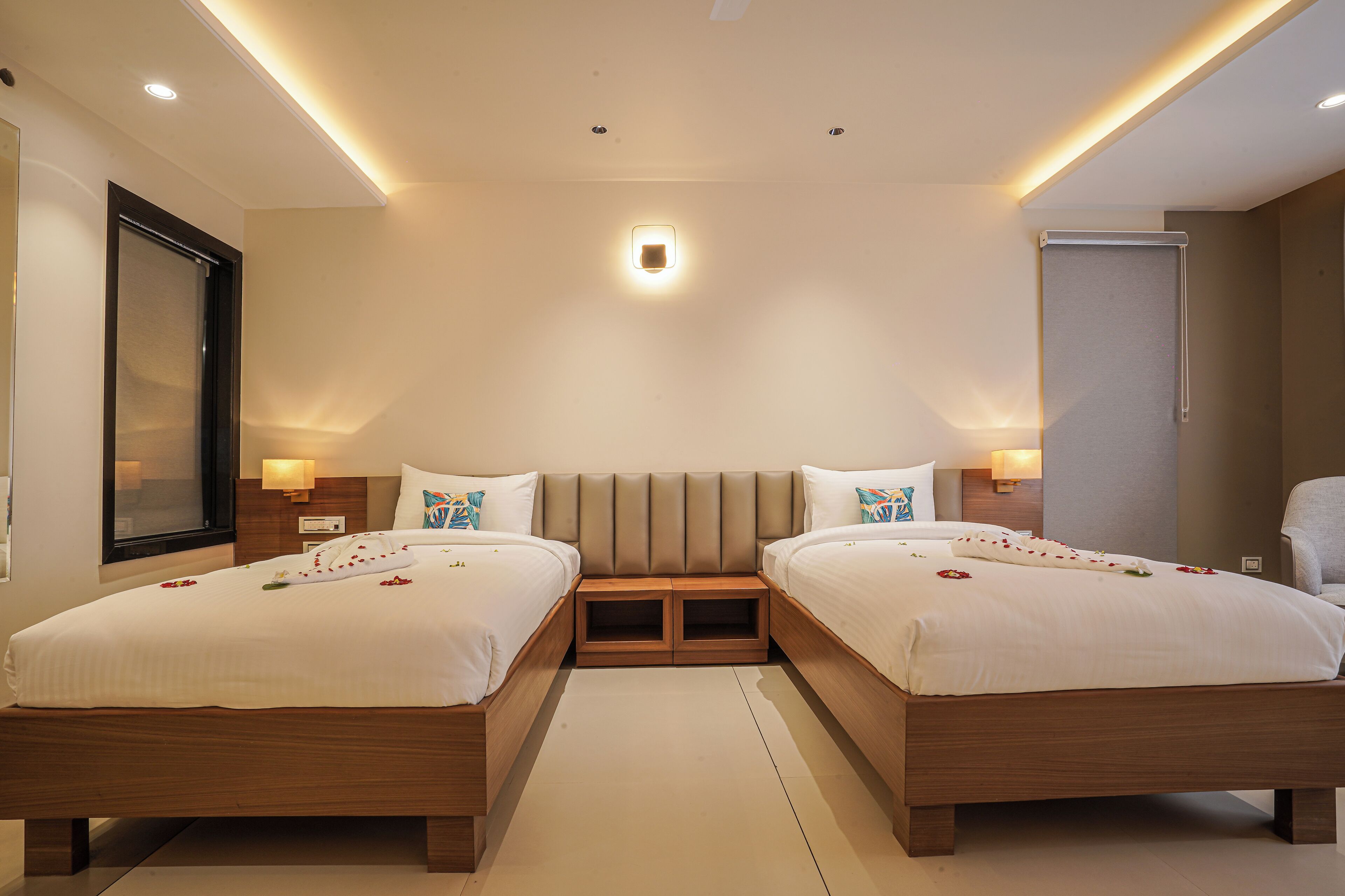 A hotel room with two beds, a large mirror, and a wardrobe.
