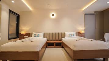 Habitación de hotel con dos camas, un espejo grande y un armario.