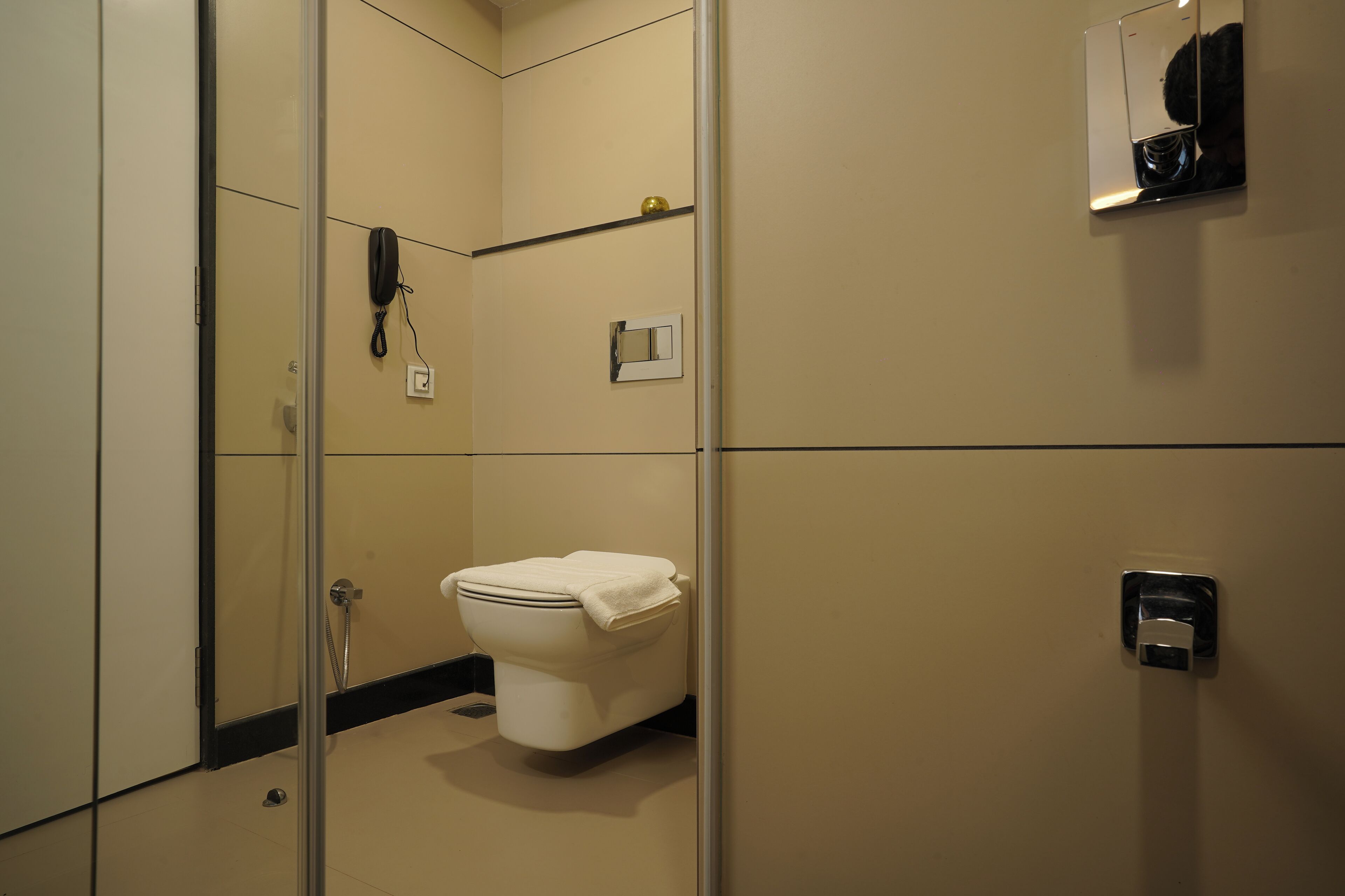 Un baño con inodoro, ducha, espejo y teléfono.