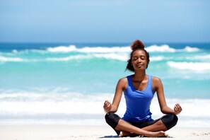 A person meditating on a beach with the ocean in the background. - Kreyol Krib Diani  (Diani Beach)