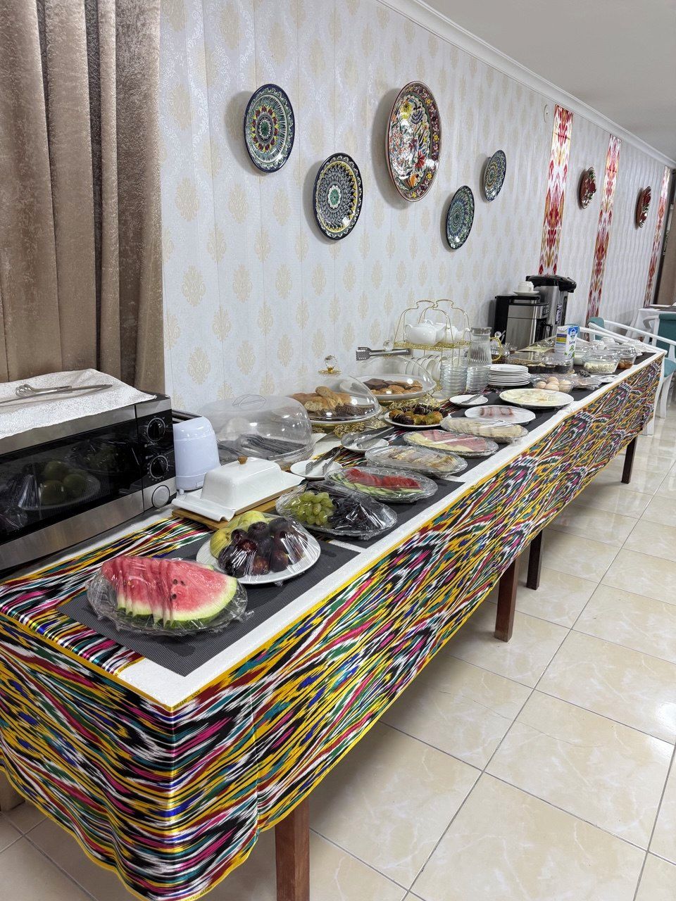 A buffet setup with a variety of food items, a microwave, and a coffee machine.