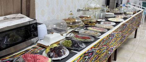 A buffet setup with a variety of food items, a microwave, and a coffee machine.