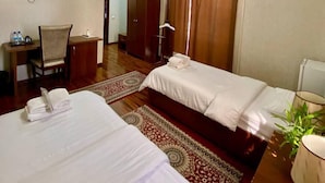 A hotel room with two beds, a desk, a TV, and a wardrobe. - Vardonze  (Bukhara)