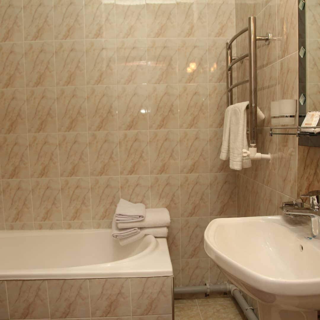 A bathroom with a bathtub, a sink, and a towel rack.