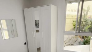 Une chambre à coucher avec un lit, une armoire et une fenêtre donnant sur un beau paysage.