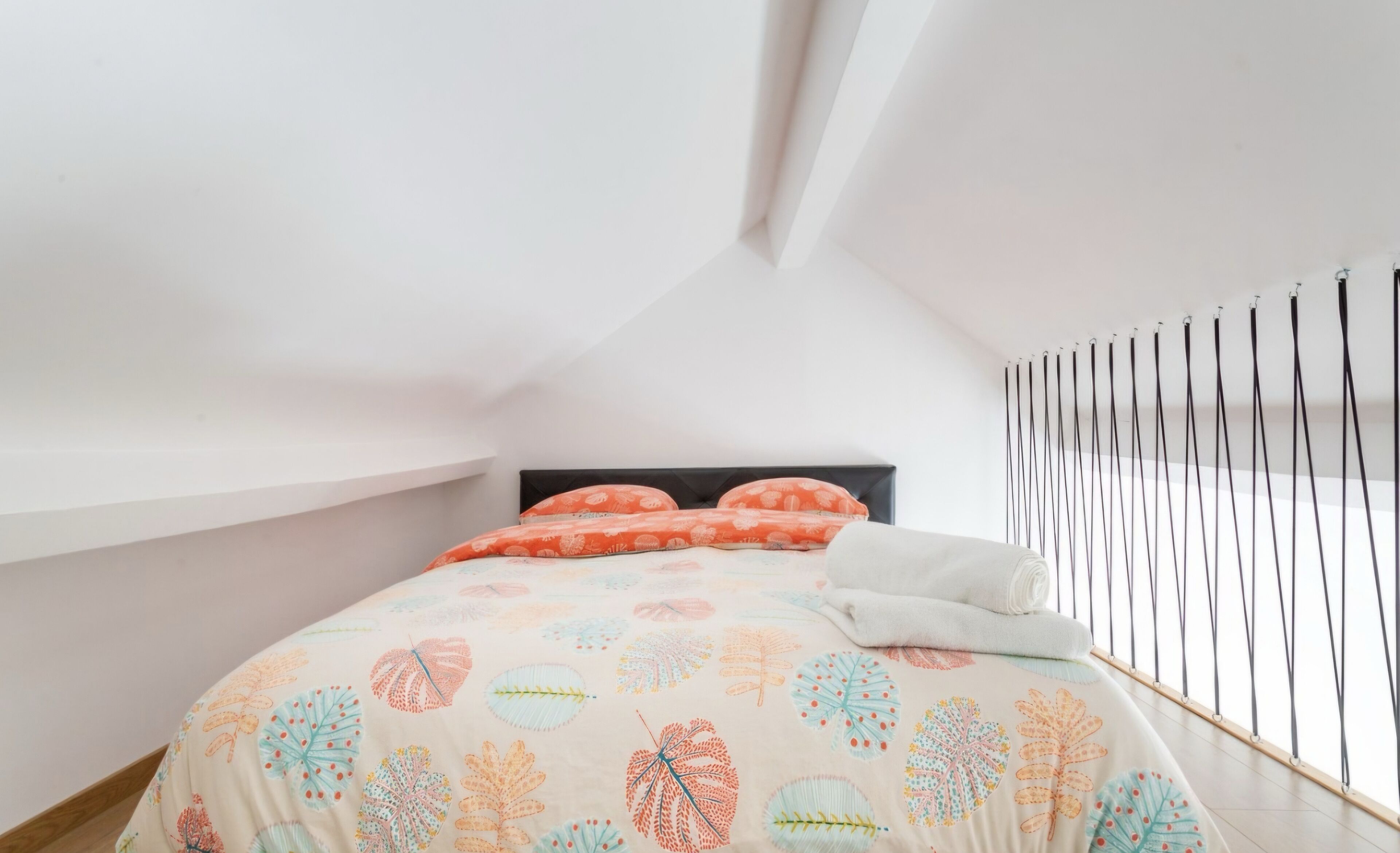A bedroom with a bed, pillows, and a window with blinds.