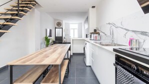 Una cocina moderna con un banco de madera, un horno empotrado y una escalera con escalones de madera.