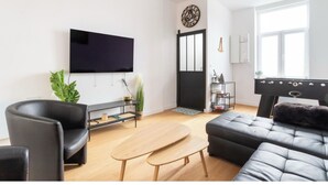 Una sala de estar moderna con un televisor de pantalla plana, un sofá, una mesa de centro y una mesa de billar.