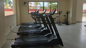A gym with multiple treadmills, a stationary bike, and a fan on the wall.