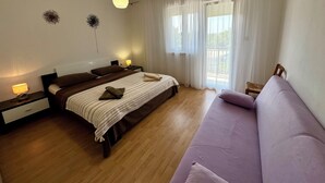 Een slaapkamer met een bed, nachtkastjes, een lamp, een bank en een raam met gordijnen.