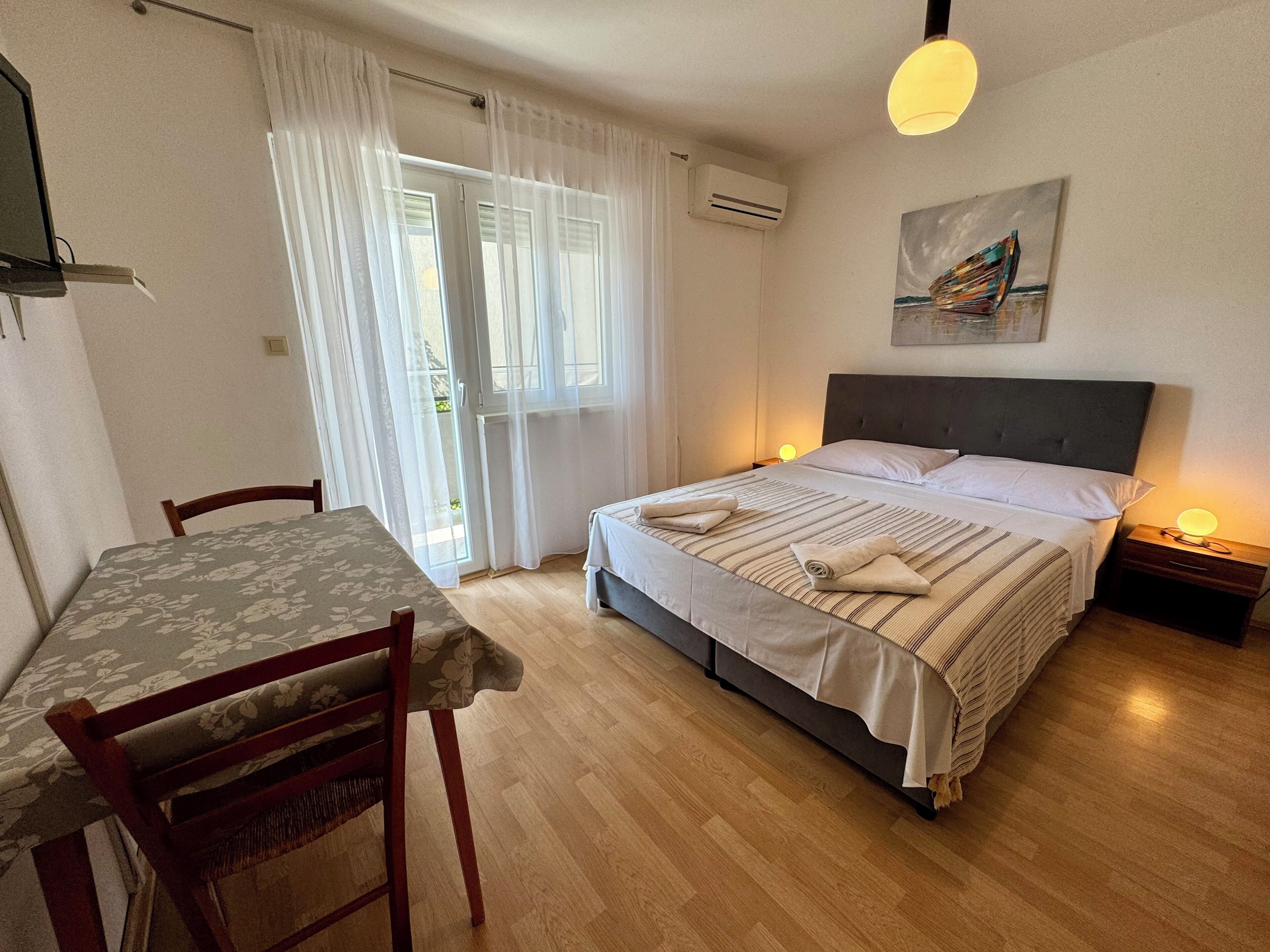 A bedroom with a bed, bedside table, and a table with chairs.