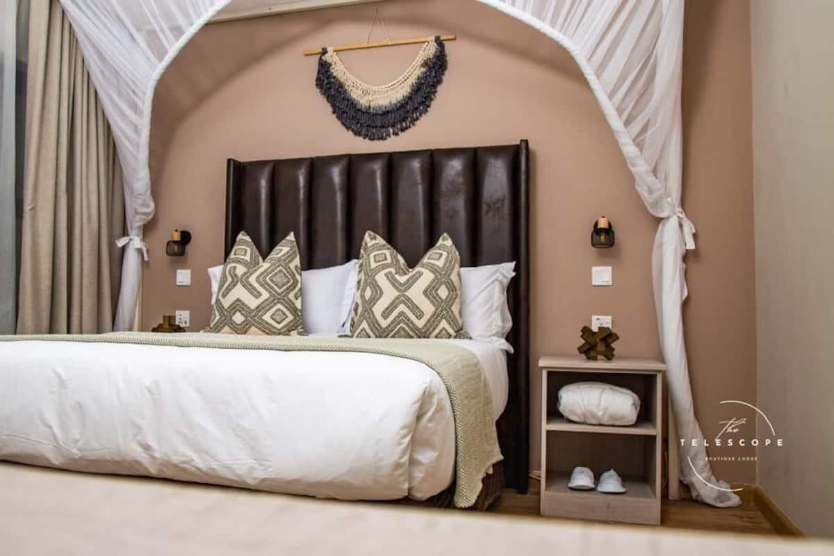 Ein Schlafzimmer mit einem großen Bett, einem Nachttisch mit Schuhen und einem Wandbild.