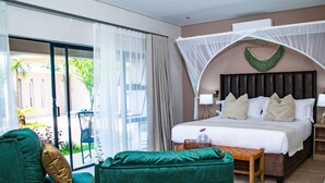 Une chambre d’hôtel avec un lit, un fauteuil vert et une petite table.