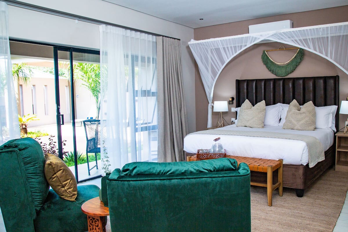 Ein Hotelzimmer mit Bett, grünem Sessel und kleinem Tisch.