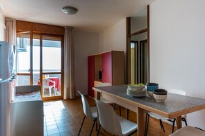 Eine moderne Küche mit Essbereich, ein Balkon mit rotem Tisch und eine Schiebeglastür.