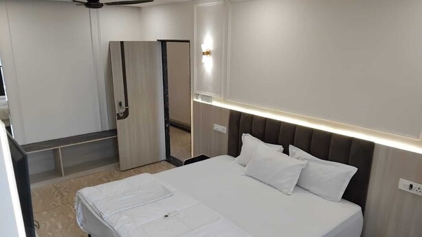 Una habitación de hotel moderna con una cama bien hecha, un ventilador de techo y un espejo grande.