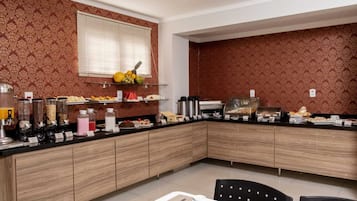 A modern kitchen with a breakfast bar, wooden cabinets, and a variety of food items displayed on the counter.