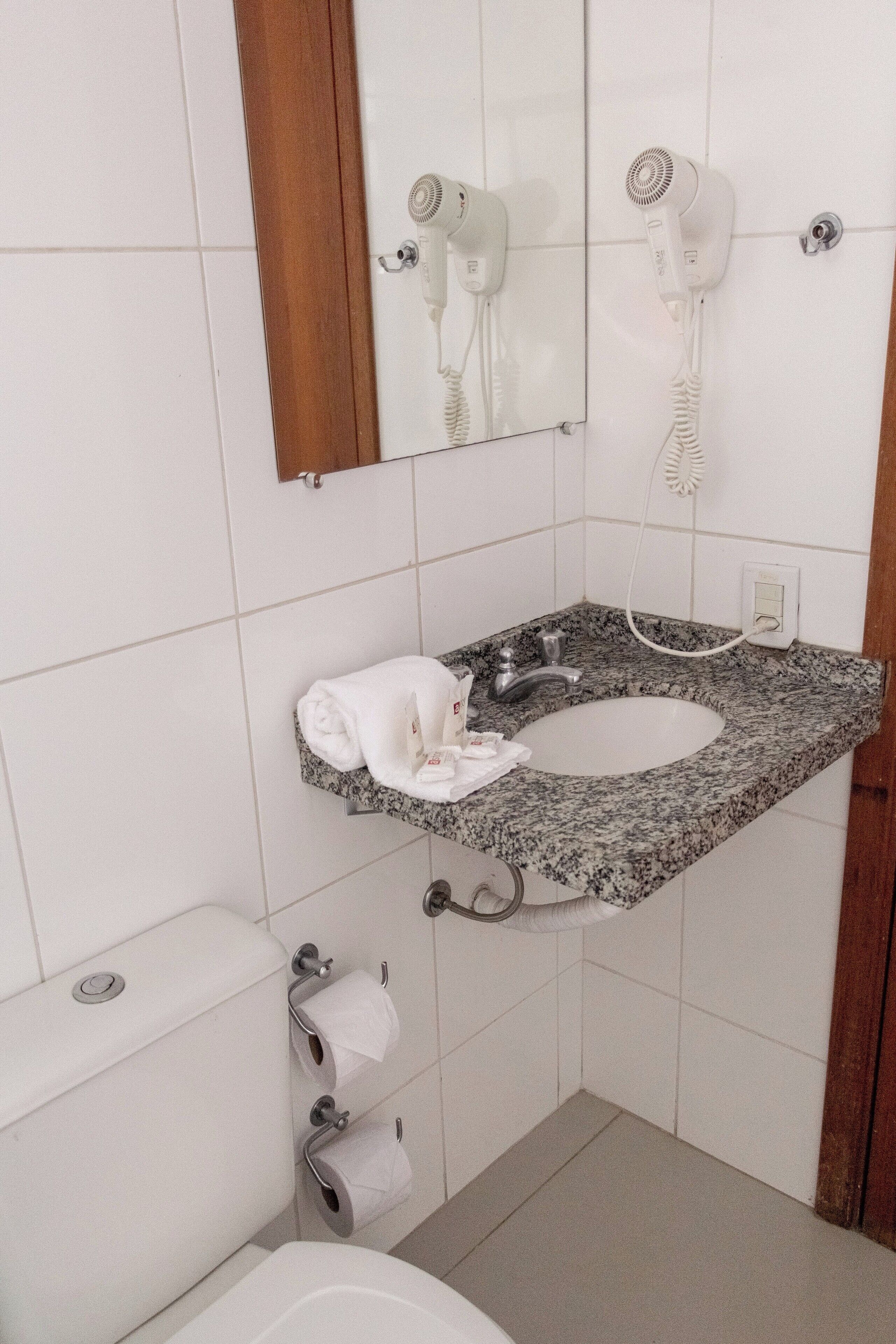 Un baño con lavamanos de granito, un espejo, una toalla y un inodoro.