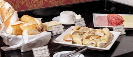 Ein Buffet mit verschiedenen Speisen, darunter Brot, Käse und Sandwiches.