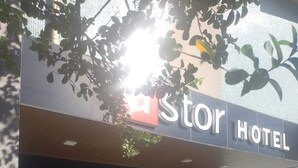 El exterior de un hotel con un letrero que dice "Stor Hotel". Hay plantas en macetas grandes frente a la entrada.